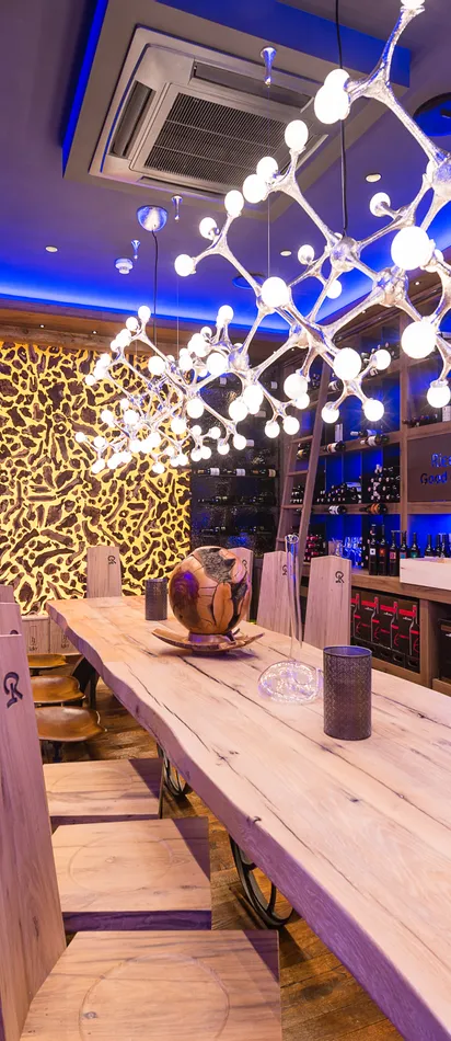 Modern wine cellar with wooden table, designer lighting, and illuminated wine bottle displays