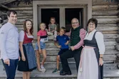 Familie in traditioneller Tracht vor Holzhütte mit Schild Hansl Alm
