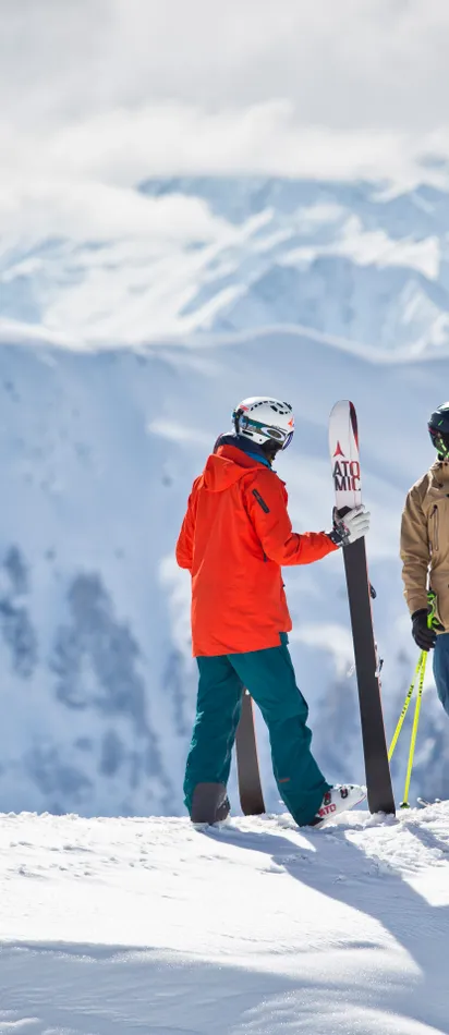 Group of skiers high-fiving on snowy mountain peak with scenic alpine backdrop