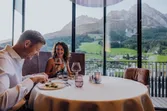 Paar beim Abendessen in einem Restaurant mit Bergblick und eleganter Tischdekoration