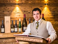Wine expert presenting Müller wines in rustic setting with bottles and wooden gift box