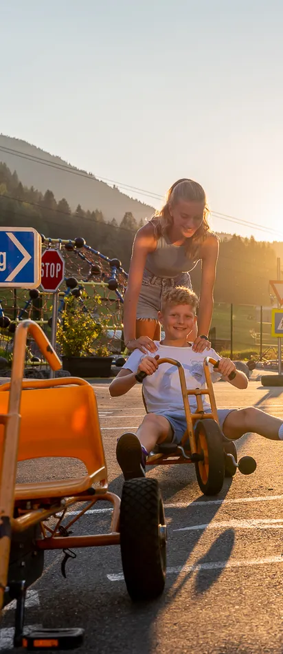 Kinder spielen mit Tretkarts an einem sonnigen Tag im Freien bei Salzburg