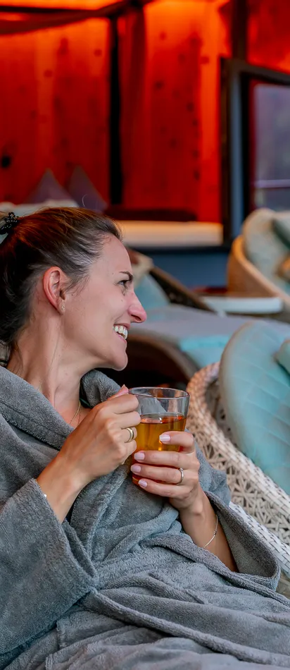 Two women in spa robes relaxing on lounge chairs and enjoying herbal tea
