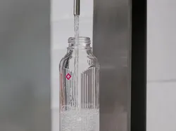 Wasserflasche wird an einem modernen Wasserspender mit stillem Wasser befüllt