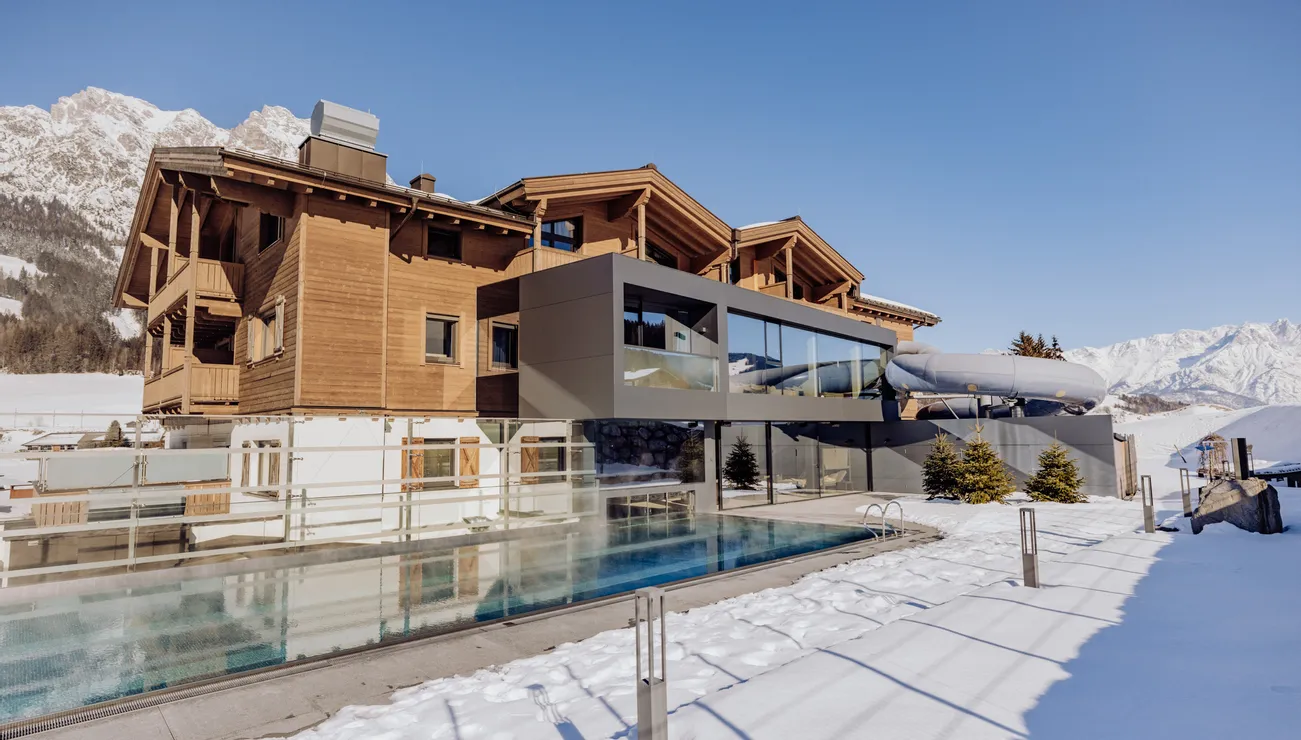 Luxuriöses Berghotel mit Außenpool im schneebedeckten Winterpanorama