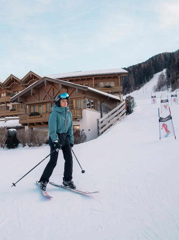 Skier on snowy slope in front of alpine ski resort with wooden chalet buildings