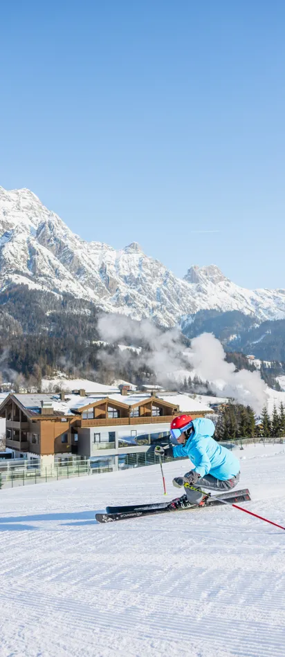 Skier carving on groomed slope with snowy Alpine mountains and chalets in background
