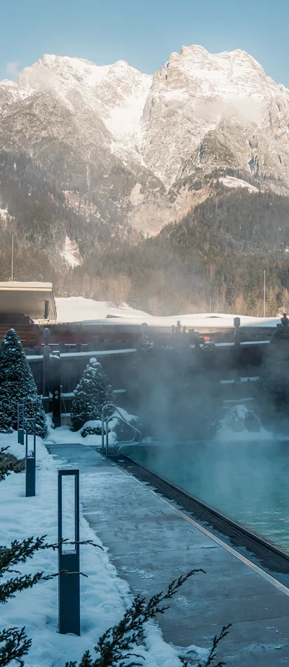 Außen-Thermalbecken in verschneitem Alpenresort mit Bergblick