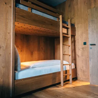 Cozy wooden bunk bed with white bedding in a rustic cabin-style bedroom