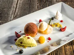 Gourmet dessert with chocolate mousse, ice cream, fruit and meringue on white plate