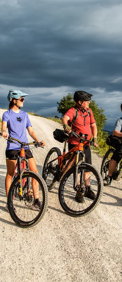Gruppe Radfahrer auf Bergpfad genießt malerische Landschaft unter bewölktem Himmel