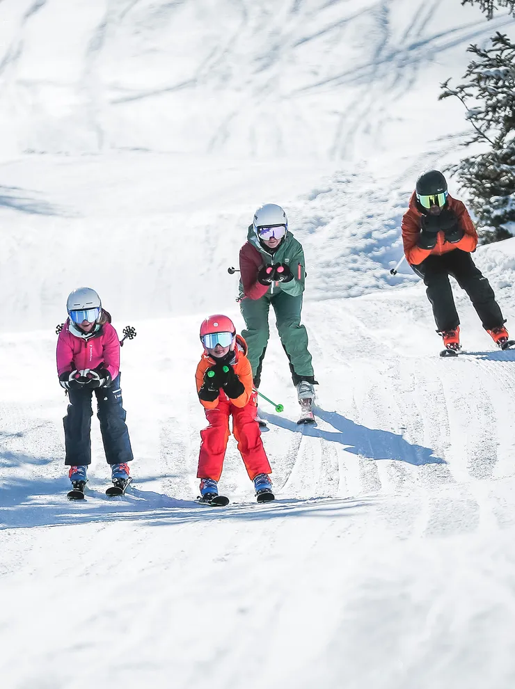 Family skiing together on a snowy mountain slope under sunny weather