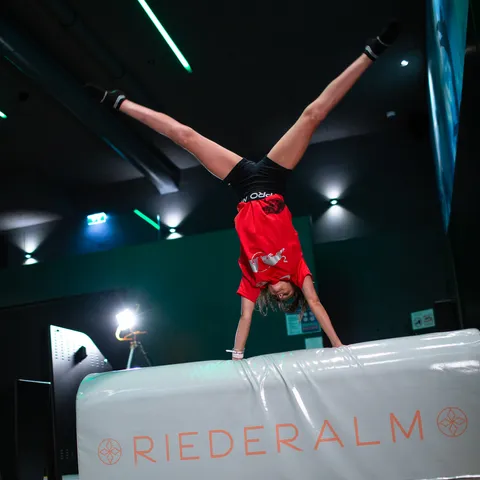 Child doing a handstand on padded vault at indoor trampoline park Riederalm