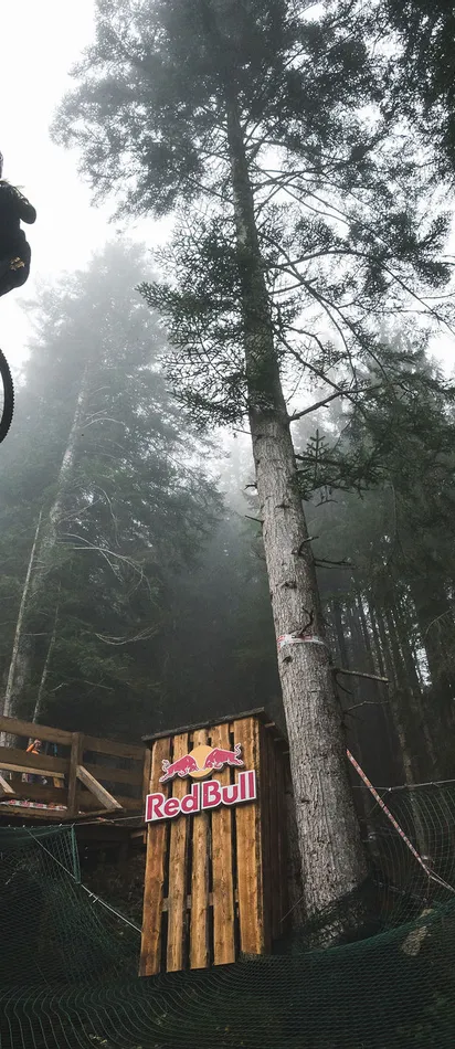 Mountainbiker springt hoch von Holzrampe bei Red Bull Event im Wald
