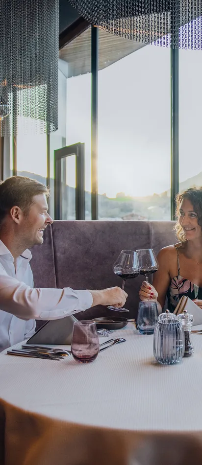 Couple enjoying fine dining with wine in elegant restaurant overlooking mountain view