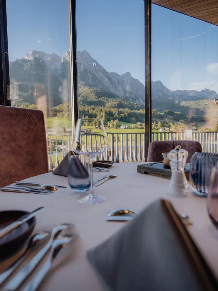 Elegant gedeckter Restauranttisch mit Panoramablick auf Berge durch große Fenster