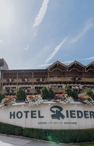 Hotel Riederalm in Leogang mit alpiner Holzarchitektur und blumengeschmückten Balkonen