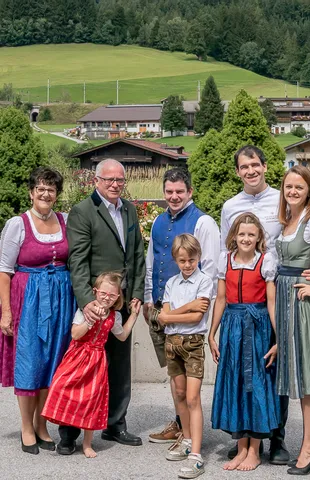 Familie in traditioneller österreichischer Tracht vor Alpenkulisse