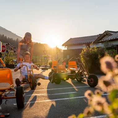 Kinder spielen mit Tretkarts an einem sonnigen Tag im Freien bei Salzburg