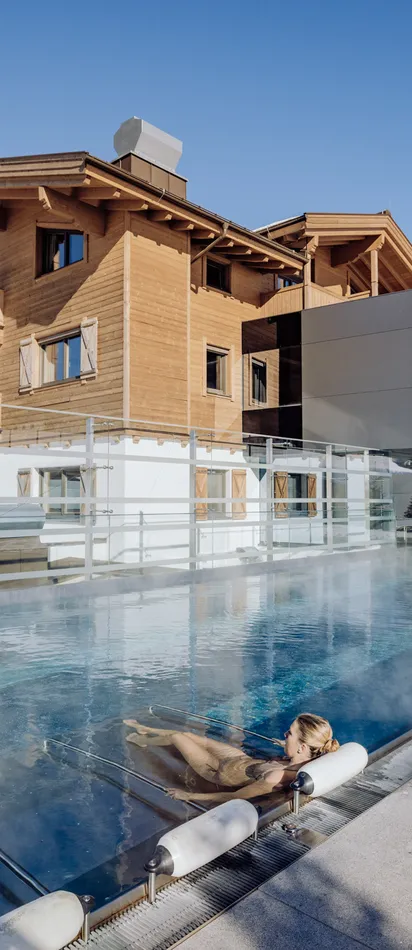 Woman relaxing in heated outdoor pool at alpine resort with snowy mountain view