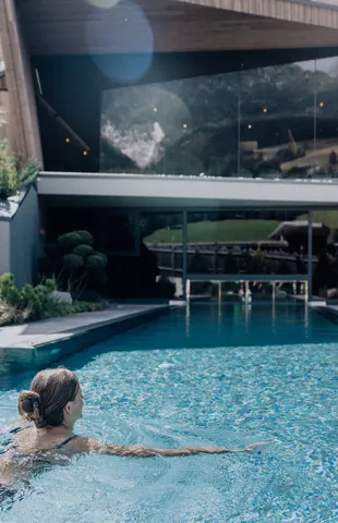 Woman swimming in a luxurious outdoor pool at a modern wellness hotel