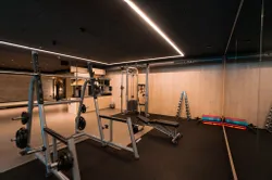 Modern gym interior with weightlifting equipment, dumbbells, and exercise mats