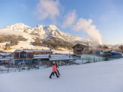 People walking through snowy alpine ski resort with mountains in background