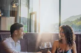 Paar genießt romantisches Abendessen mit Wein in elegantem Restaurant bei Sonnenuntergang