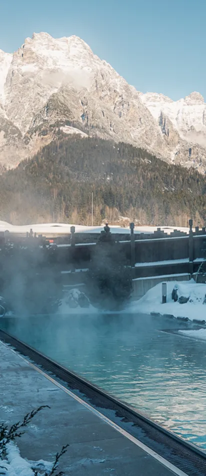 Thermalbecken im Freien in verschneitem Alpinresort mit Bergblick