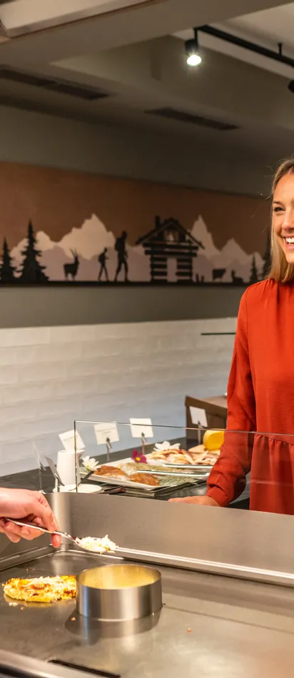 Koch serviert lächelnder Frau frisches Essen an Buffetstation im Restaurant