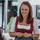 Smiling woman in traditional Bavarian dirndl standing outdoors at a restaurant