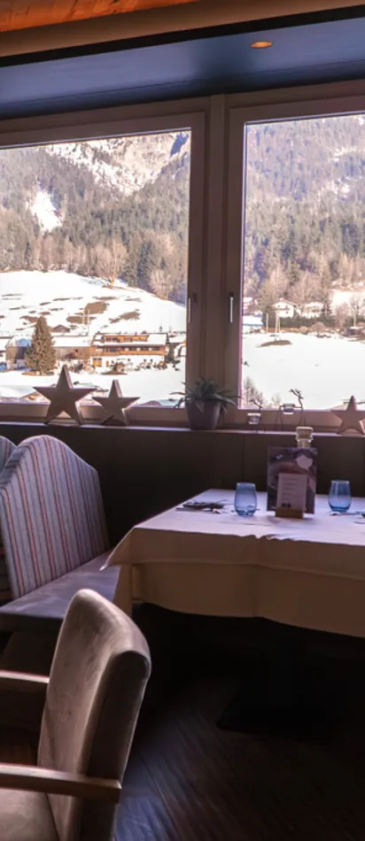 Gemütliches Alpenrestaurant mit Blick auf schneebedeckte Berge durch große Fenster