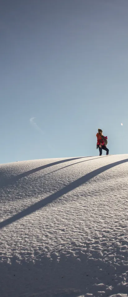Two people hiking in sunny snowy landscape on a winter day