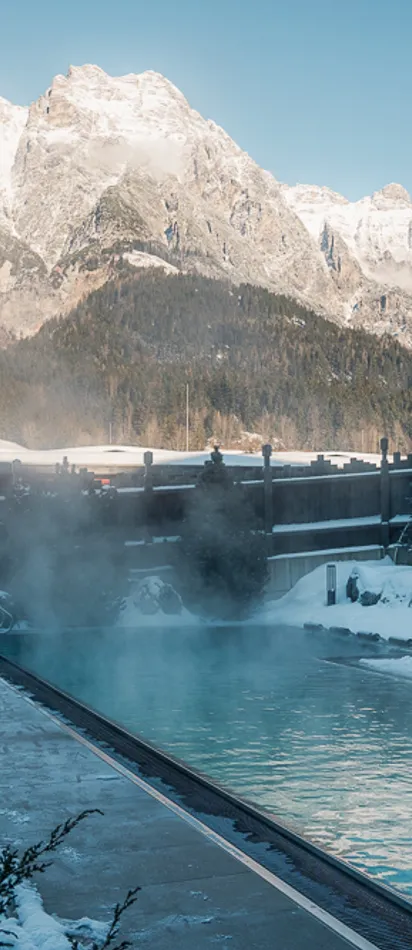 Outdoor thermal pool in snowy alpine resort with mountain view