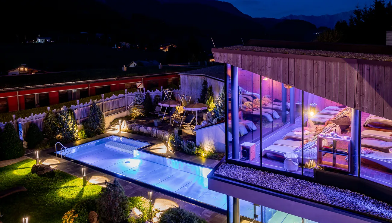 Luxury spa hotel with outdoor pool and illuminated relaxation area at night