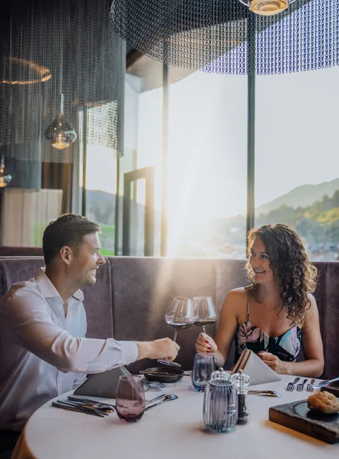 Couple enjoying romantic dinner with wine in elegant restaurant at sunset
