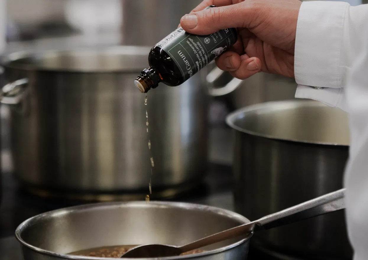 Chef adding liquid seasoning to saucepan in professional kitchen
