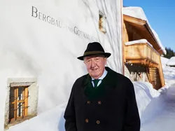 Elderly man in winter coat standing outside Mining and Gothic Museum in snowy village