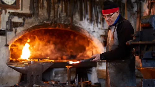 Blacksmith working with heated metal in traditional forge workshop