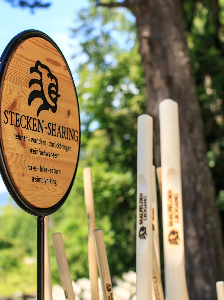 Wooden hiking stick sharing station with sign in forest setting