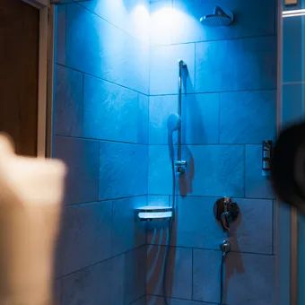 Modern tiled shower with blue LED lighting and chrome showerhead