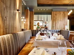 Elegantes Restaurant mit gedeckten Tischen, Holzwänden und offener Küche im Hintergrund