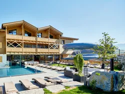 Alpine resort with outdoor pool, wooden facade, and large water slide under sunny skies