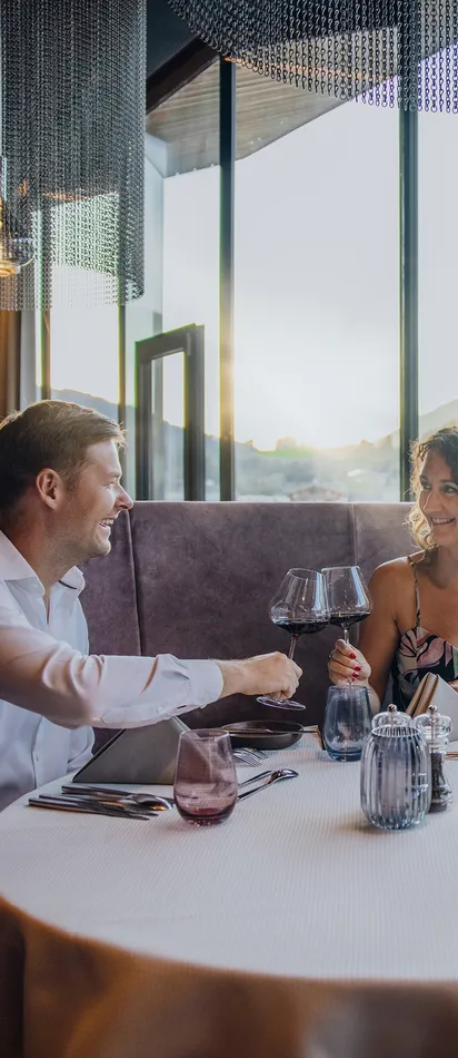Paar genießt gehobenes Essen mit Wein in elegantem Restaurant mit Bergblick