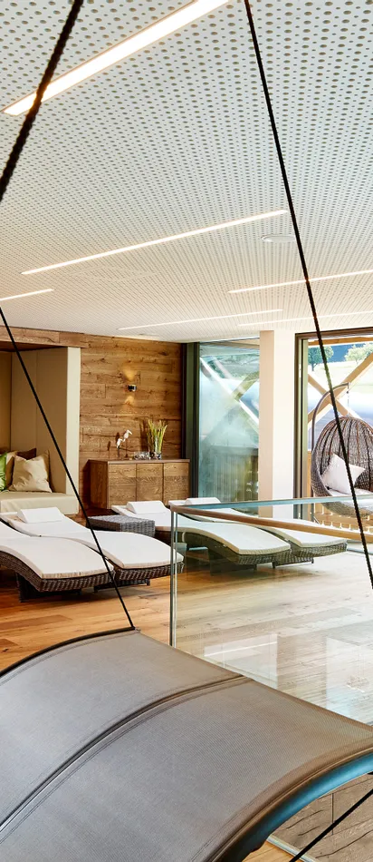 Modern spa relaxation room with loungers, hanging chair and panoramic window view