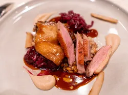 Gourmet-Entenbrust mit Rotkohl, Soße, Püree und Wurzelgemüse auf einem edlen Teller