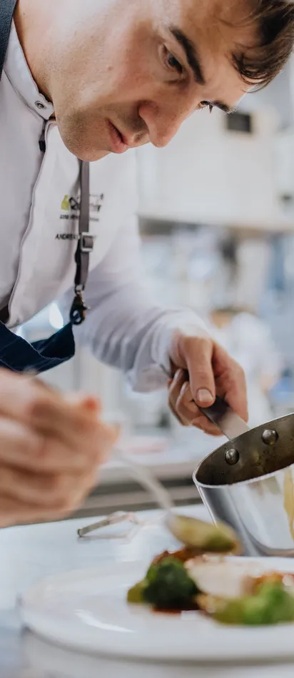 Koch richtet Gourmetgericht mit Sauce in professioneller Restaurantküche an