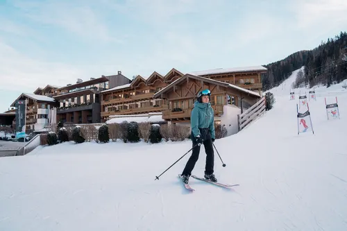 Skier on snowy slope in front of alpine ski resort with wooden chalet buildings