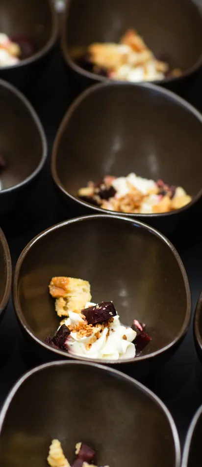 Small black bowls with gourmet dessert topped with cream, fruit, and crumbles