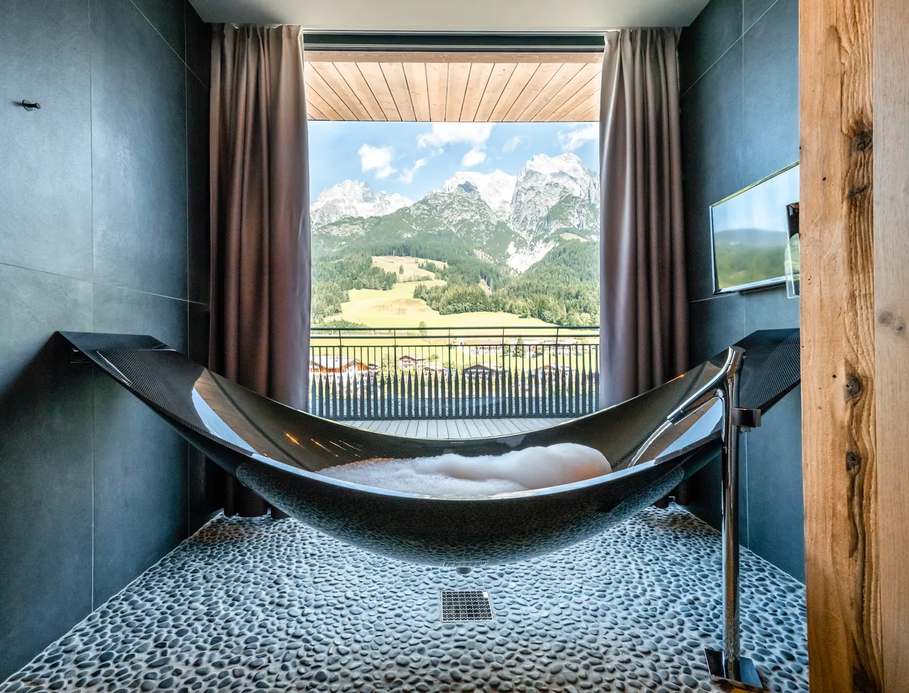 Modern freestanding bathtub with mountain view from luxury hotel room